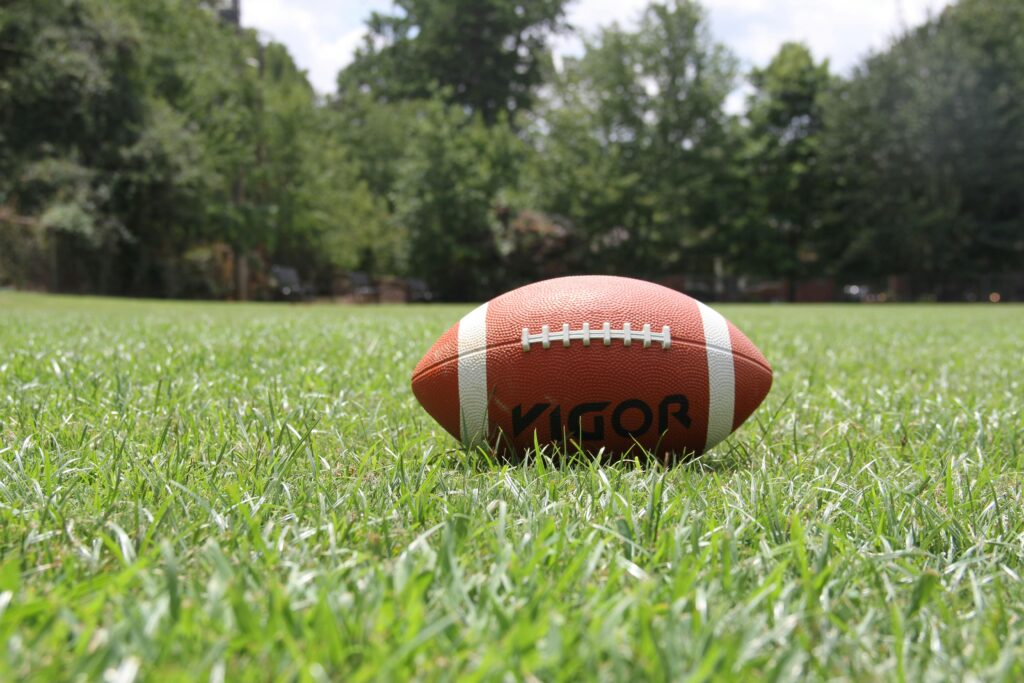 pexels-photo-209956-209956-1 A close-up of an American football on a grassy field, highlighting outdoor sports in summer.