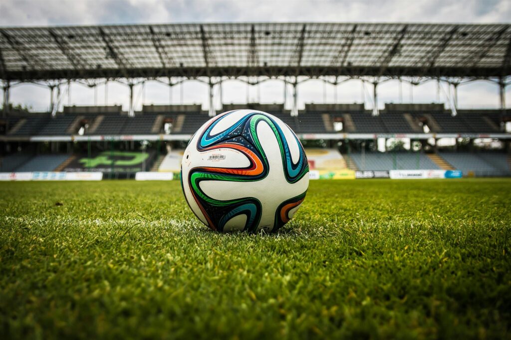 the-ball-stadion-football-the-pitch-47730-47730 A vibrant soccer ball rests on a lush green field inside an empty stadium, capturing the essence of sports.